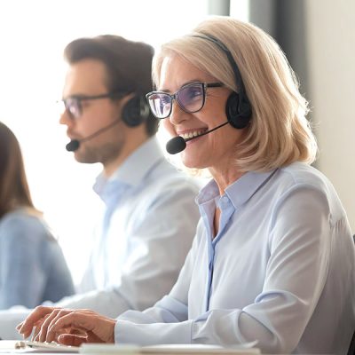 TelefonSounds.de - Smiling old female call center agent in headset consulting client
